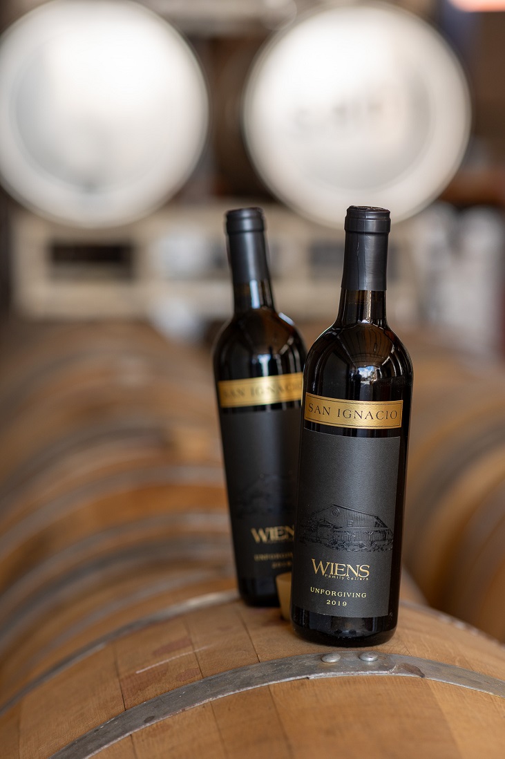 two bottles of wine on a wine barrel in a production facility