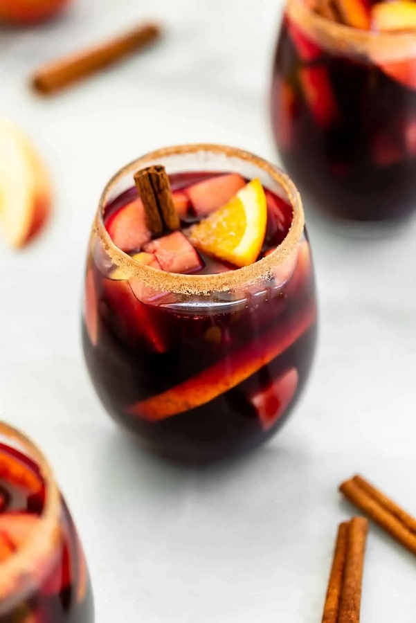 apple cider sangria fall recipe with cinnamon stick surrounding a cup in a white background