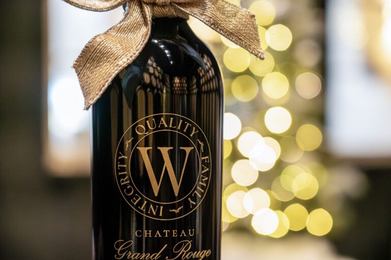 beautiful dark wine bottle with christmas tree behind it and large bow on top for decoration