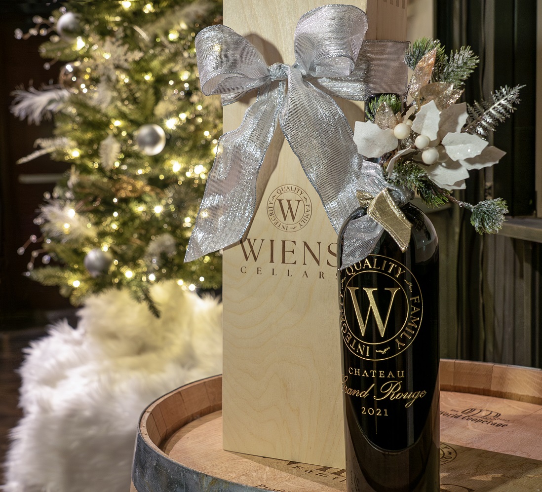 grnad rouge magnum bottle next to holiday tree with large silver bow and wooden wine box for packaging